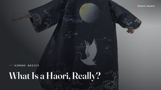 Homme portant un haori bleu nuit orné d'une lune, d'une grue et de vagues japonaises, vu de dos