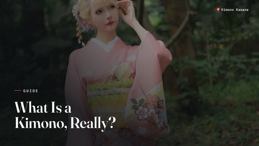 Woman wearing a pink floral furisode kimono with an obi, standing in a garden, illustrating what a kimono is